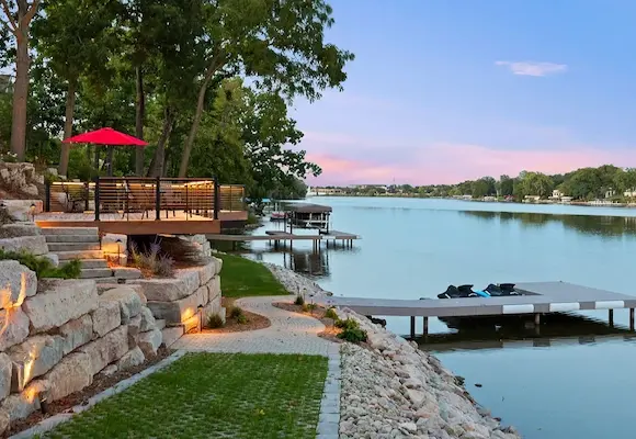 Lakeside backyard with fresh grass, a dock over the water, and a newly built deck
