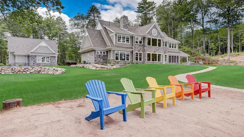 lakefront backyard with rainbow chairs on a sandy shore
