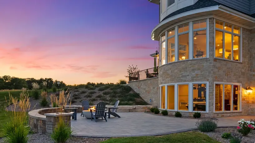 Patio on a beautiful luxury home featuring a stone tile walkway and patio with a fire pit during sunset