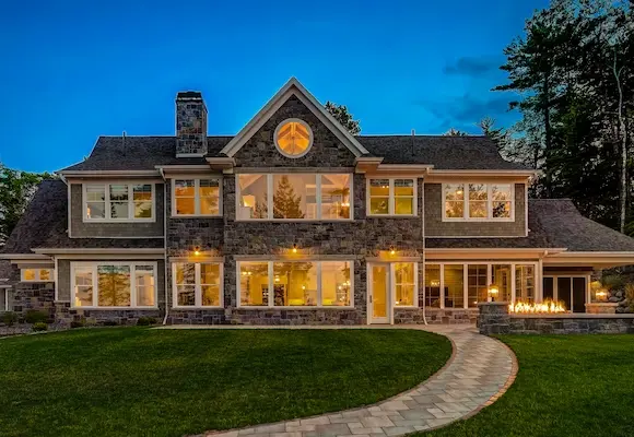 Newly built luxury home with stone exterior, massive windows, and white trim